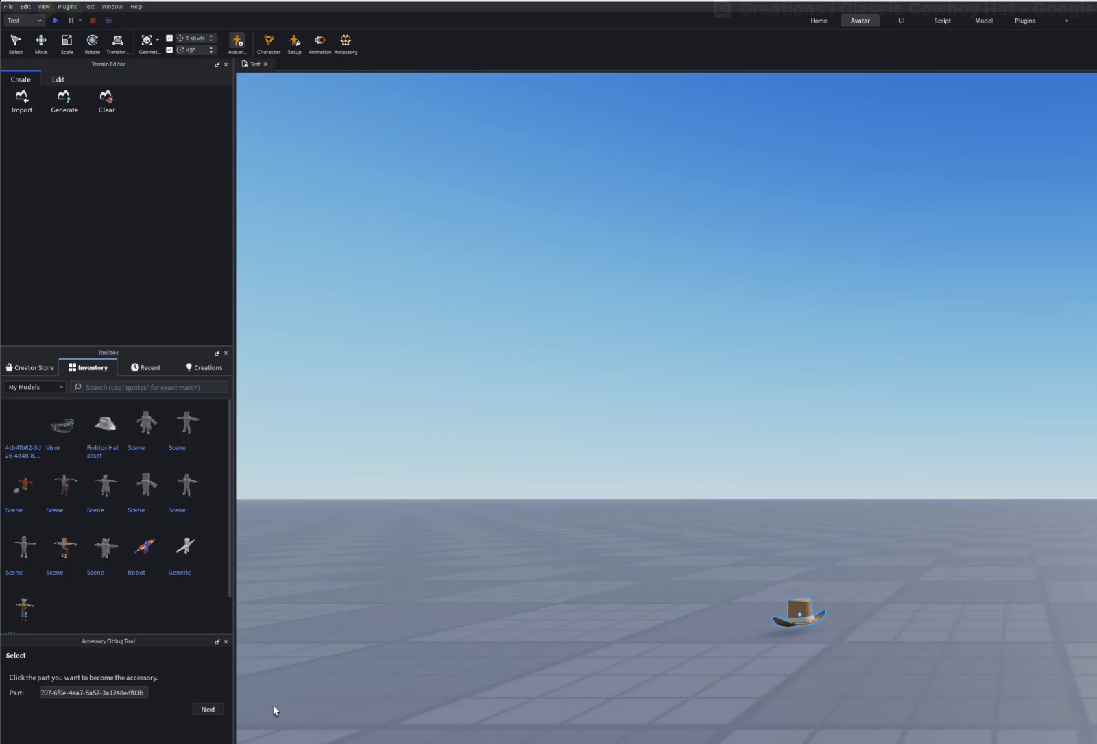 Screenshot of Roblox Studio showing a wide 3D workspace with a flat gray baseplate and blue sky. A low-poly brown cowboy hat accessory is placed in the scene near the bottom right and highlighted with a blue outline. The Inventory panel is open on the left with imported models, and the Accessory Fitting Tool panel is visible at the bottom left prompting the user to select a part to become the accessory.